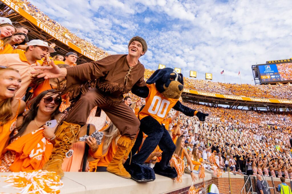 Mascot Smokey and Mascot Davey Crockett dance together on the sidelines during a Vol football game