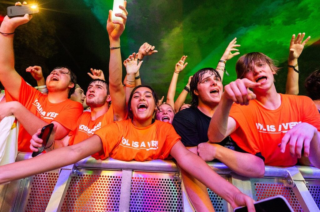 Students clad in orange Vol is a Verb t-shirts at an outdoor concert