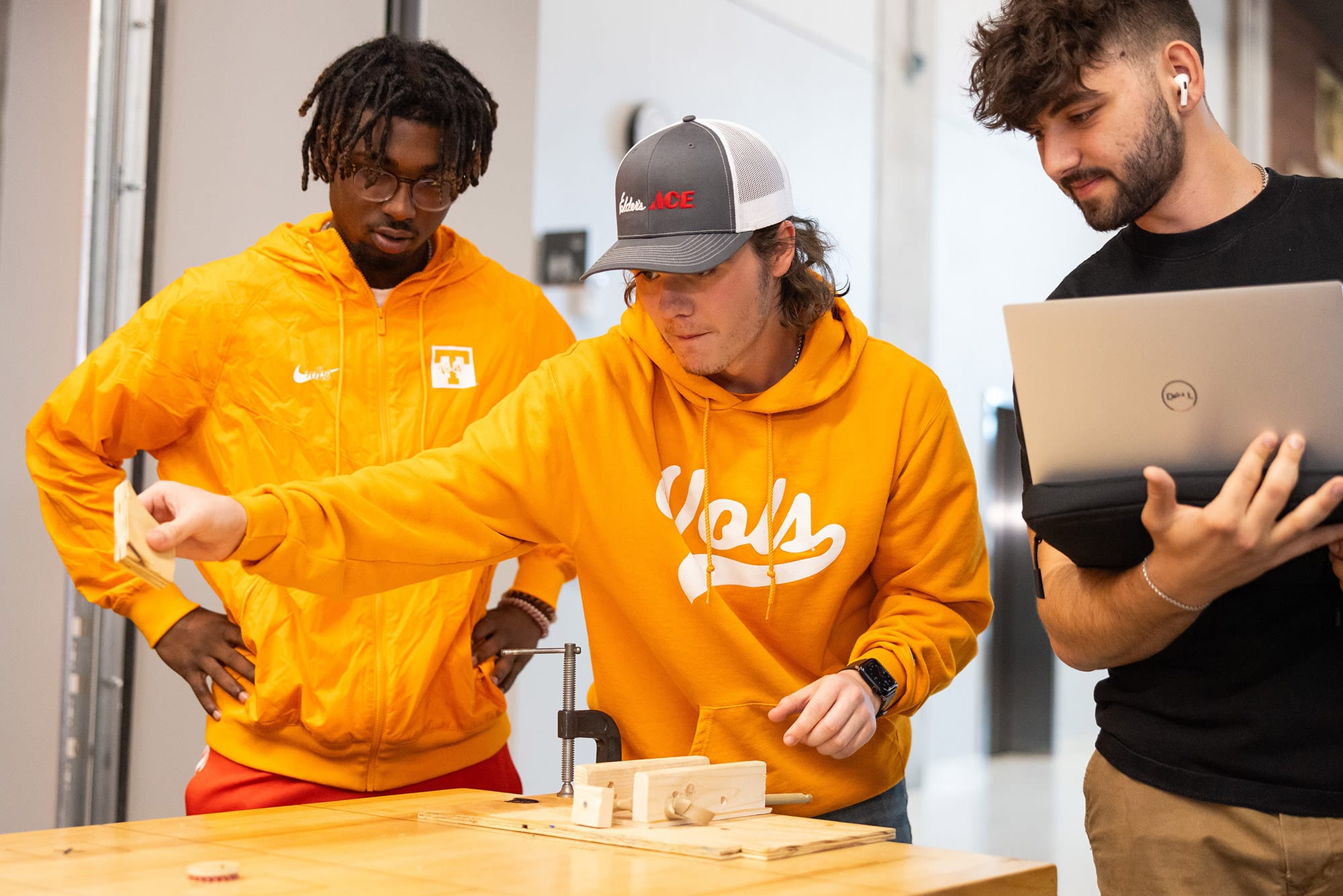 Students wearing bright orange sweatshirts are doing a physics experiment