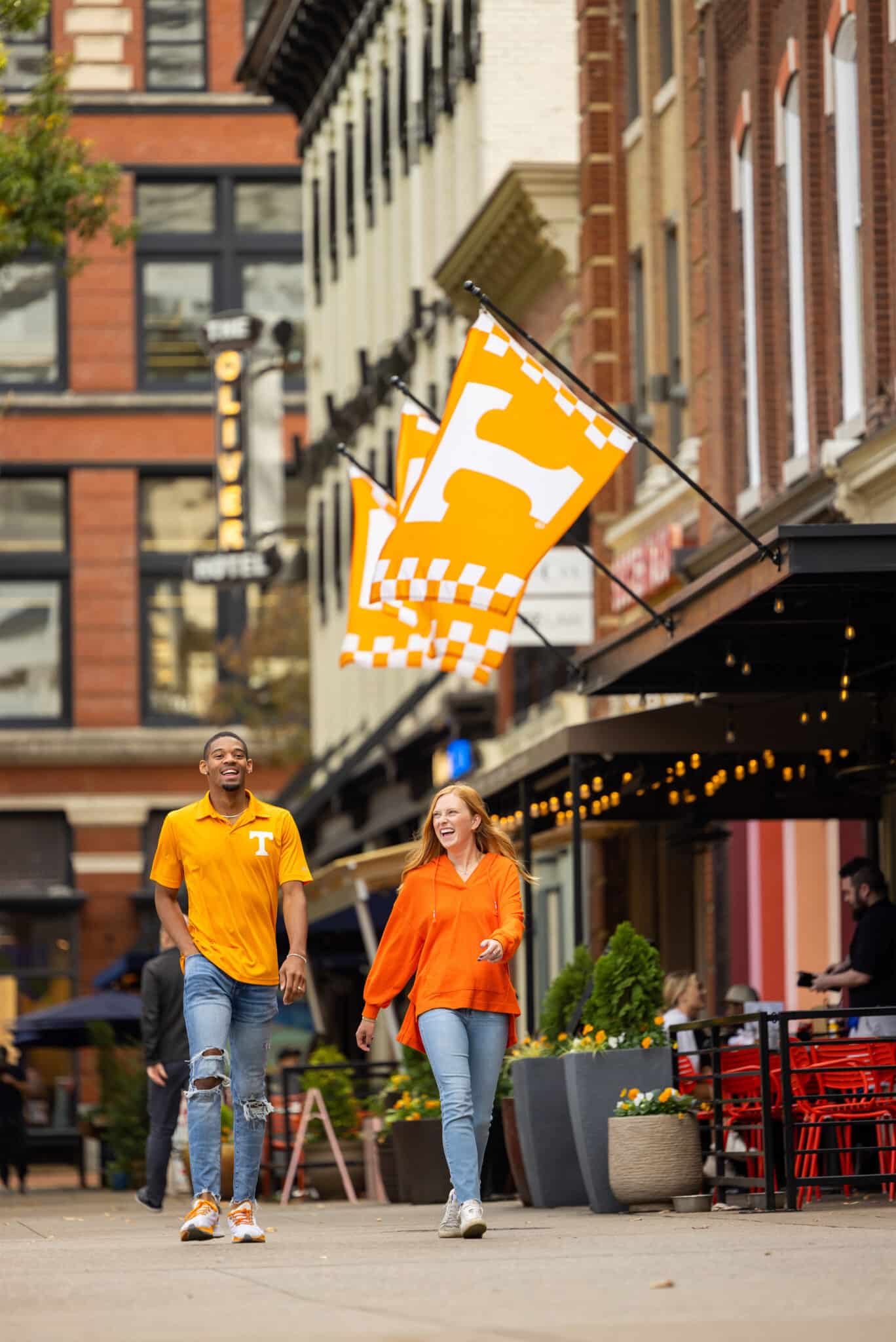 Students walk across Market Square, passing under a big UT flag hanging over the entrance to a business
