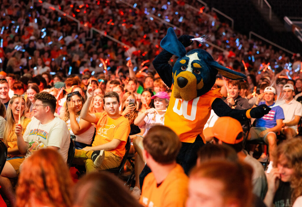 Mascot Smokey crowdsurfs through a sea of orange clad students on Torch Night