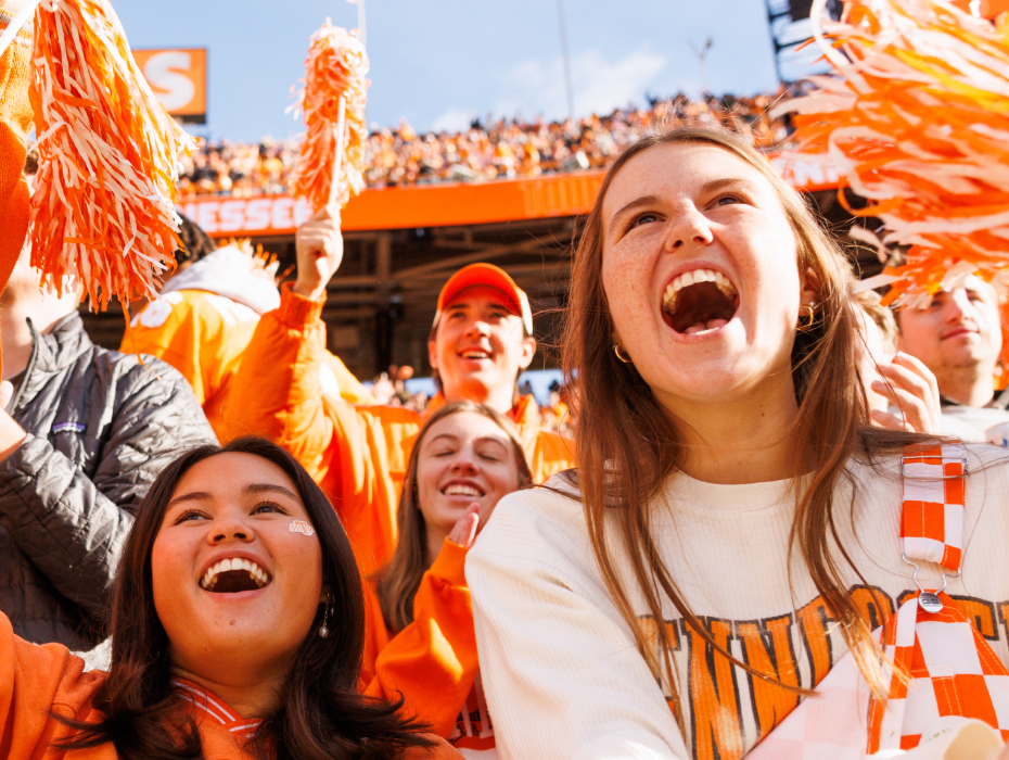 Students cheer at a UT football game, surrounded by orange