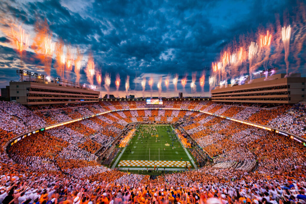Neyland Stadium at night, lit up by fireworks, with the crowd in an orange and white checkerboard pattern