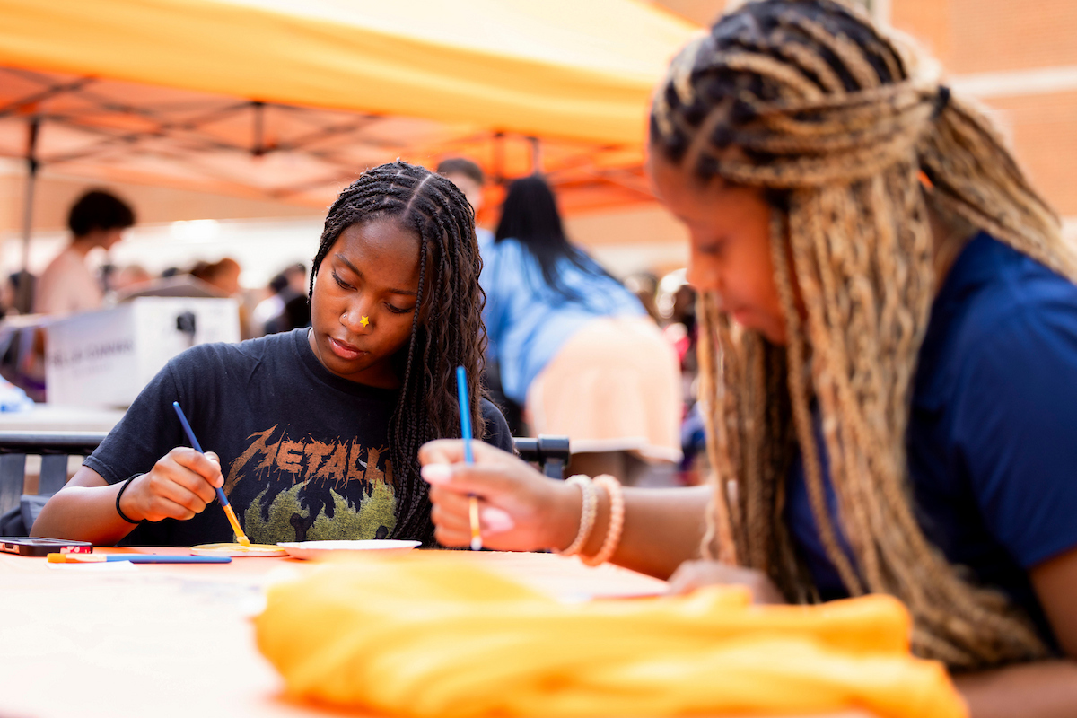 Students paint at a table under an orange canopy during Welcome Week Bash hosted by Student Engagement at the Student Union Plaza on August 21, 2025. Photo by Craig Bisacre/University of Tennessee.